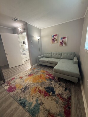 A living room with a sectional sofa, a colorful rug, and two abstract paintings on the wall. - Cozy 1-bedroom condo in Burlington, pet friendly  (Burlington)