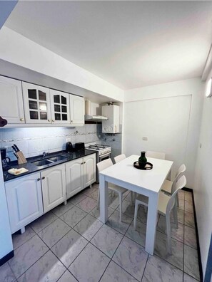 Enjoy meals in this kitchen with a gas stove and coffee maker, adjacent to a dining table for four.
