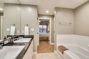 Een moderne badkamer met twee wastafels, een grote spiegel en een bad.