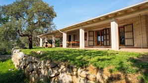 Una casa moderna con fachada de piedra, ventanas amplias y un área de patio techada.