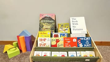 Una estantería de madera con una variedad de libros infantiles, incluyendo títulos como 'One Fish' y 'El Gato Ensombrerado'.