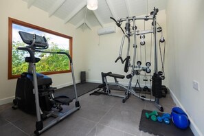 Un gimnasio en casa con cinta de correr, banco de pesas y diversos equipos de ejercicio.