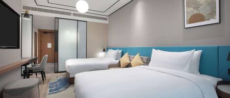 A hotel room with two beds, a desk, a chair, a large painting, and a blue accent wall.