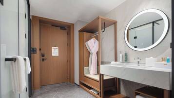 Un baño moderno con tocador de madera, un espejo redondo y un perchero para toallas.