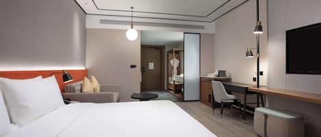 Una habitación de hotel moderna con una cama grande, un escritorio, una silla y un televisor.