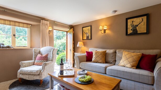 A living room with a sofa, armchair, and a coffee table with a bottle and glasses.