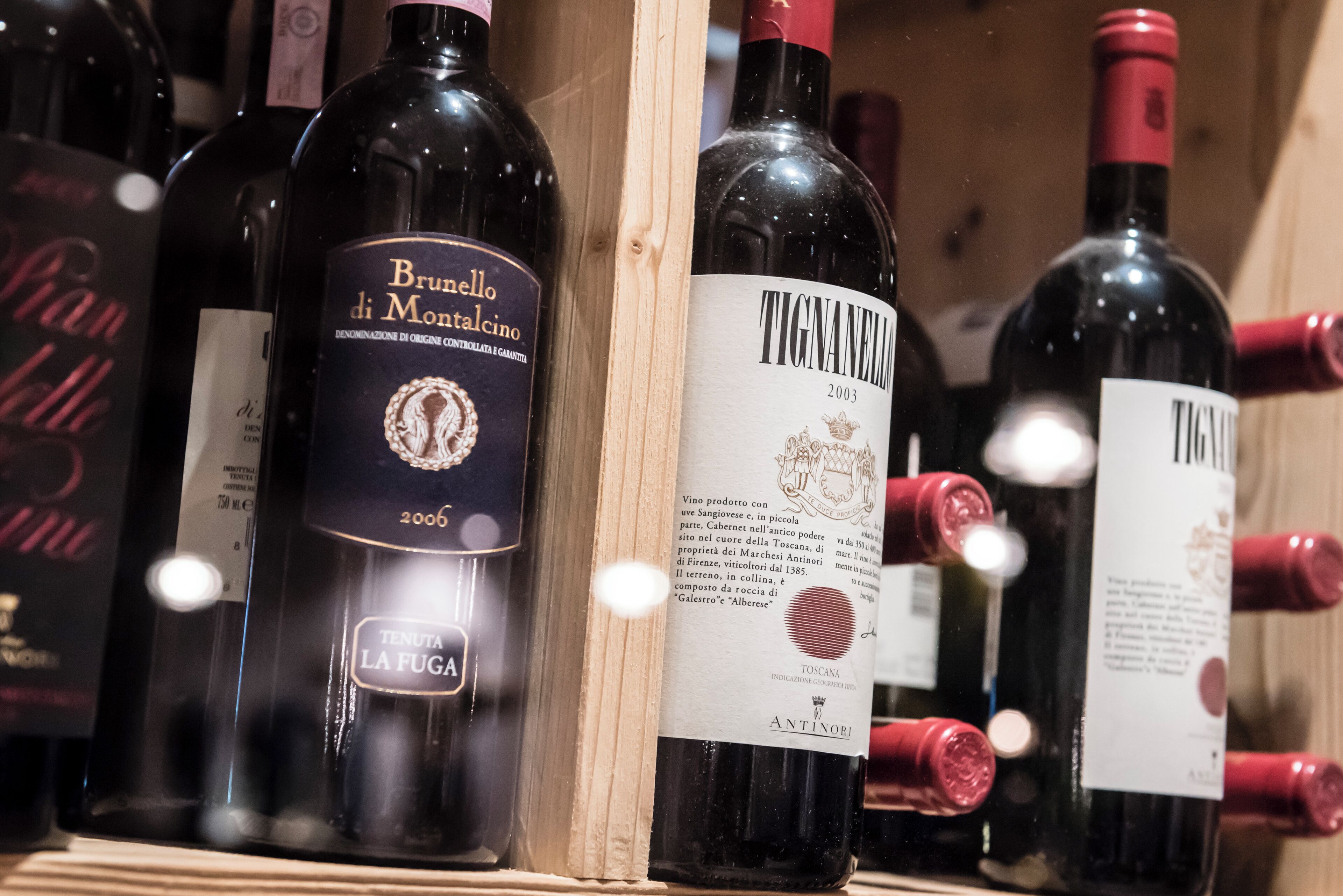 Una colección de botellas de vino con etiquetas, incluyendo 'Brunello di Montalcino' y 'Tignanello'.