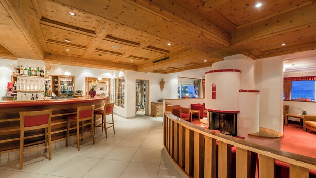 A bar area with wooden chairs, a counter with bottles, and a fireplace. - Residence Mathilda in the Vinschgau apple orchard - Refined & simple (Schlanders)