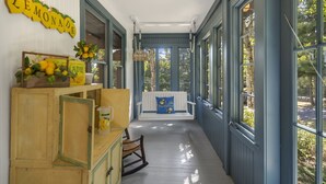 Un porche cubierto con un banco de madera, una mecedora y un letrero que dice "LEMONADE".
