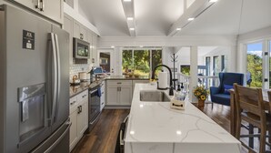 Una cocina moderna con una isla grande, electrodomésticos de acero inoxidable y vistas al exterior.