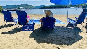 Une plage avec des chaises bleues et un panneau indiquant qu’une fête est organisée sur la plage.