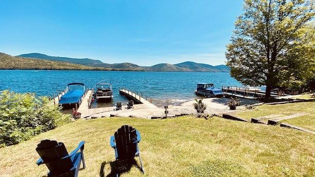 Une jetée au bord du lac, avec des bateaux, des chaises et une vue dégagée sur le lac et les montagnes.