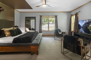 A bedroom with a bed, a chair, a TV, a ceiling fan, and a window with curtains. - Bolton Bear House|Dock Slip|Hot Tub|12 Beds|Pet Friendly| (Bolton Landing)