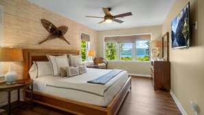 A bedroom with a wooden bed, a ceiling fan, a view of the outdoors, and a large window. - Lakeview Lodge|Hot Tub|9 Beds|Pet Friendly|Dock Slip|Lake Views| (Bolton Landing)