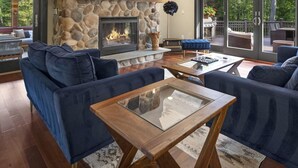 Una sala de estar acogedora con chimenea de piedra, sofás azules y una mesa de centro de vidrio.