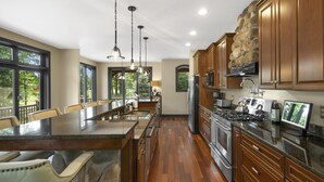 Una cocina amplia con una isla grande, armarios de madera y una pared de acento de piedra.