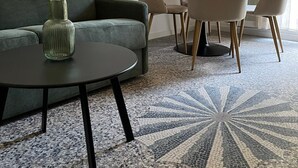 Un salon moderne avec un canapé vert, une table basse ronde et une table à manger avec des chaises.