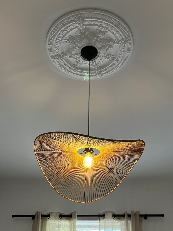 A ceiling with an ornate circular design and a hanging light fixture with a woven shade.