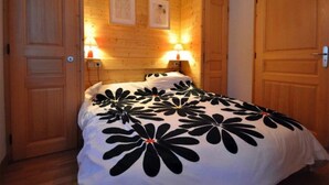 Ein Schlafzimmer mit Bett, Holzwänden, zwei Wandleuchten und einer Tür.