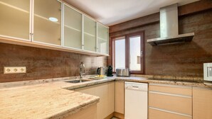 A kitchen with a granite countertop, white cabinets, a dishwasher, and a window with blinds. - Apartment with Sea Views (Jávea)