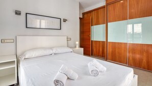 A hotel room with a large bed, wooden wardrobe, and a framed picture on the wall. - Apartment with Sea Views (Jávea)
