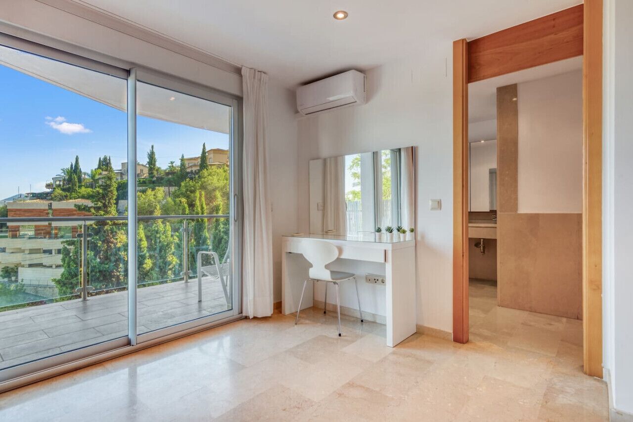 A modern bathroom with a large window, a white vanity, and a mirror.