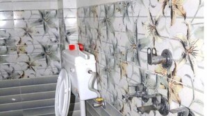 A bathroom with a toilet, a wall-mounted sink, and a toilet paper holder. - Kunal Guest House  (Varanasi)
