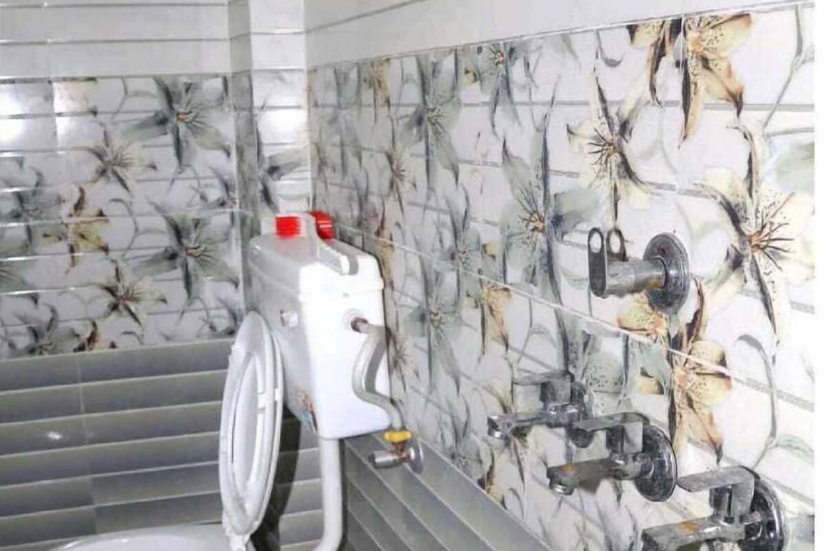 Un baño con inodoro, lavamanos empotrado y dispensador de papel higiénico.