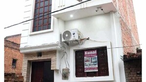 A two-story building with a white facade, a balcony on the upper floor, and a sign advertising a guest house. - Kunal Guest House  (Varanasi)
