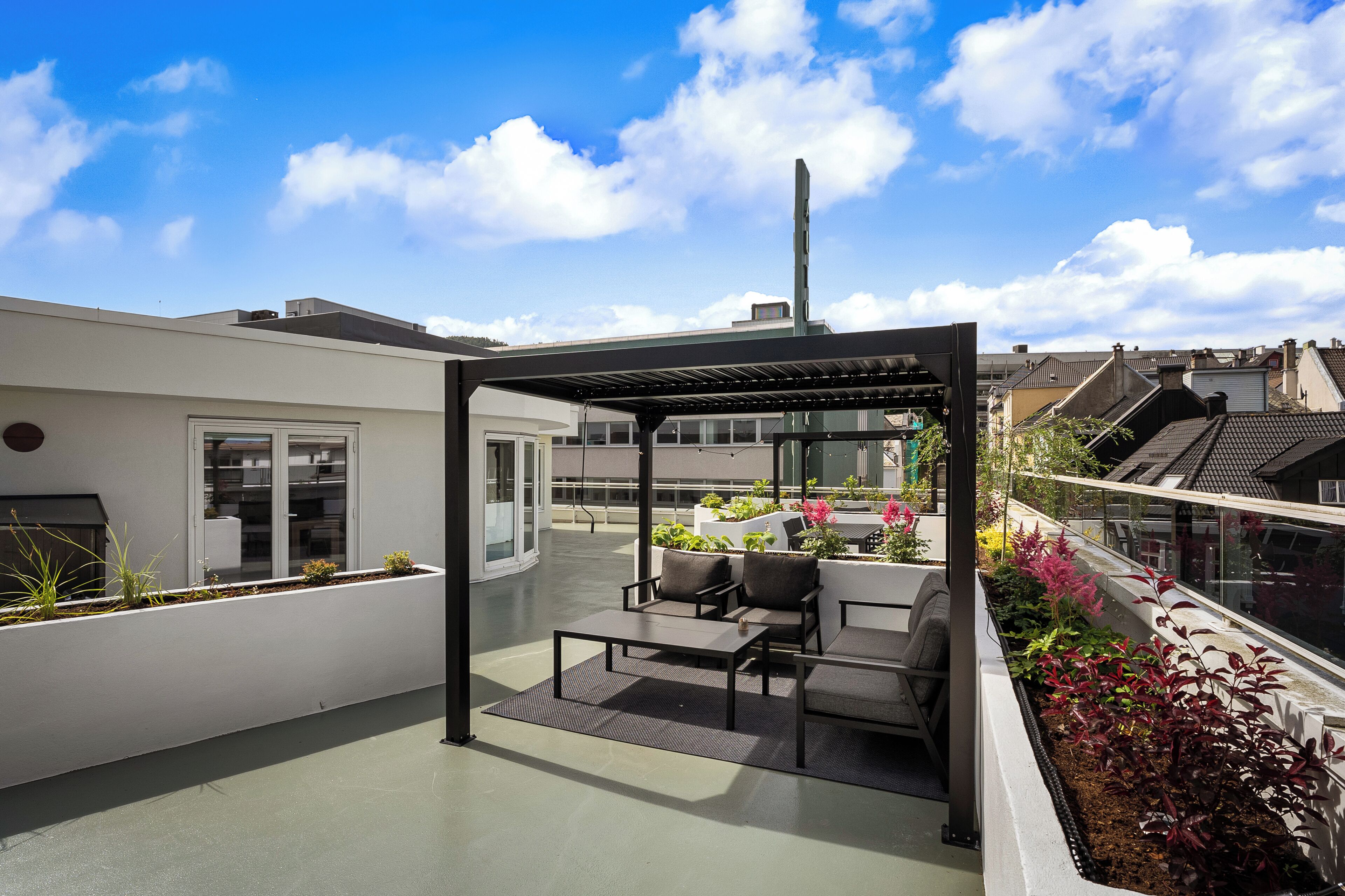 A rooftop terrace with a glass enclosure, outdoor seating, and a garden.