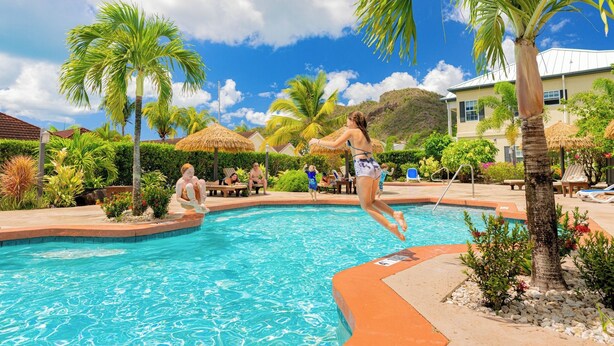 A swimming pool with palm trees and lounge chairs. - Three Bedroom Superior Apartment (Jolly Harbour)