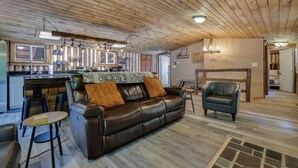 A cozy cabin interior with a wooden ceiling, a leather sofa, a dining area, and a kitchen with wooden cabinets. - Cozy Log Cabin in Jim Thorpe (Jim Thorpe)