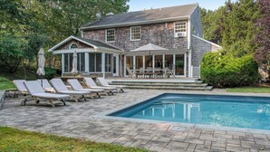 A house with a swimming pool, a covered patio with outdoor furniture, and a garden. - Expansive Modern Sag Harbor Home with Private Heated Pool, Perfect for Families (Sag Harbor)