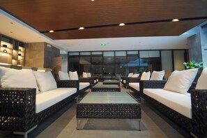 A modern lobby with wicker sofas, a glass coffee table, and a wooden ceiling. - Bayprime Hotel (Paranaque)