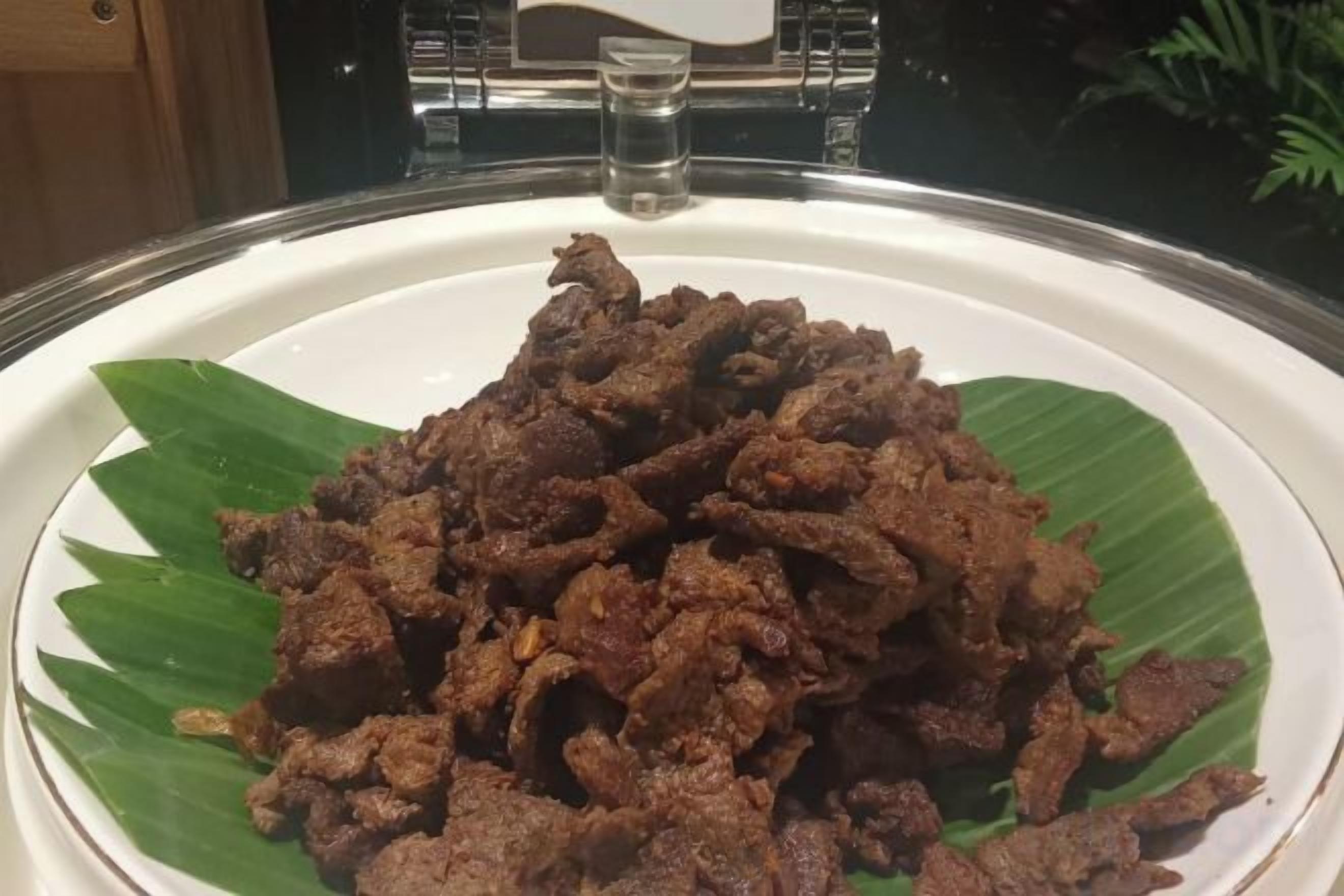 A plate of cooked meat on a banana leaf.