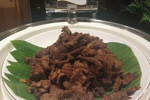 Une assiette de viande cuite servie sur une feuille de bananier.