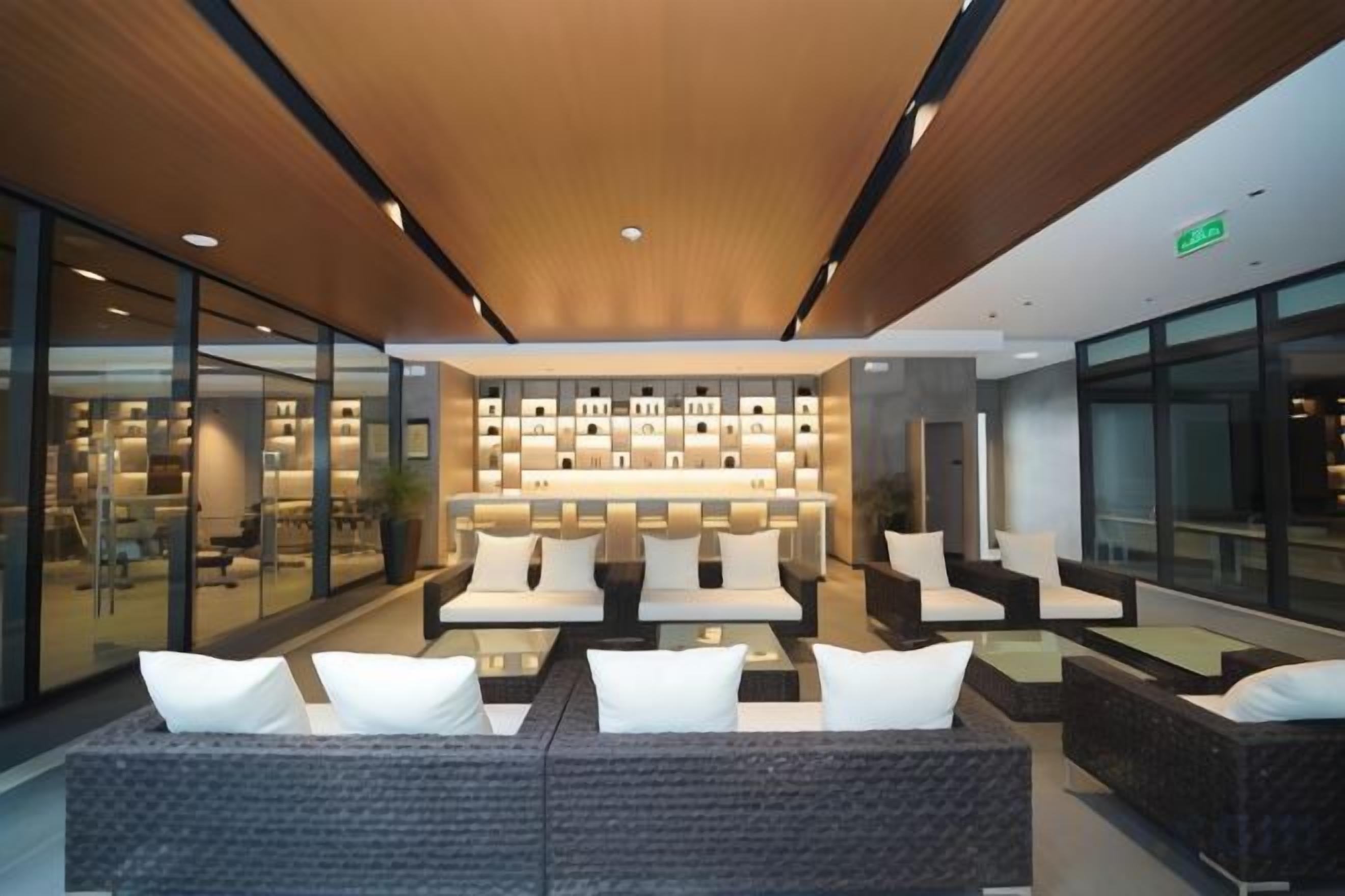 A modern lobby with a central seating area, glass walls, and a ceiling with recessed lighting.