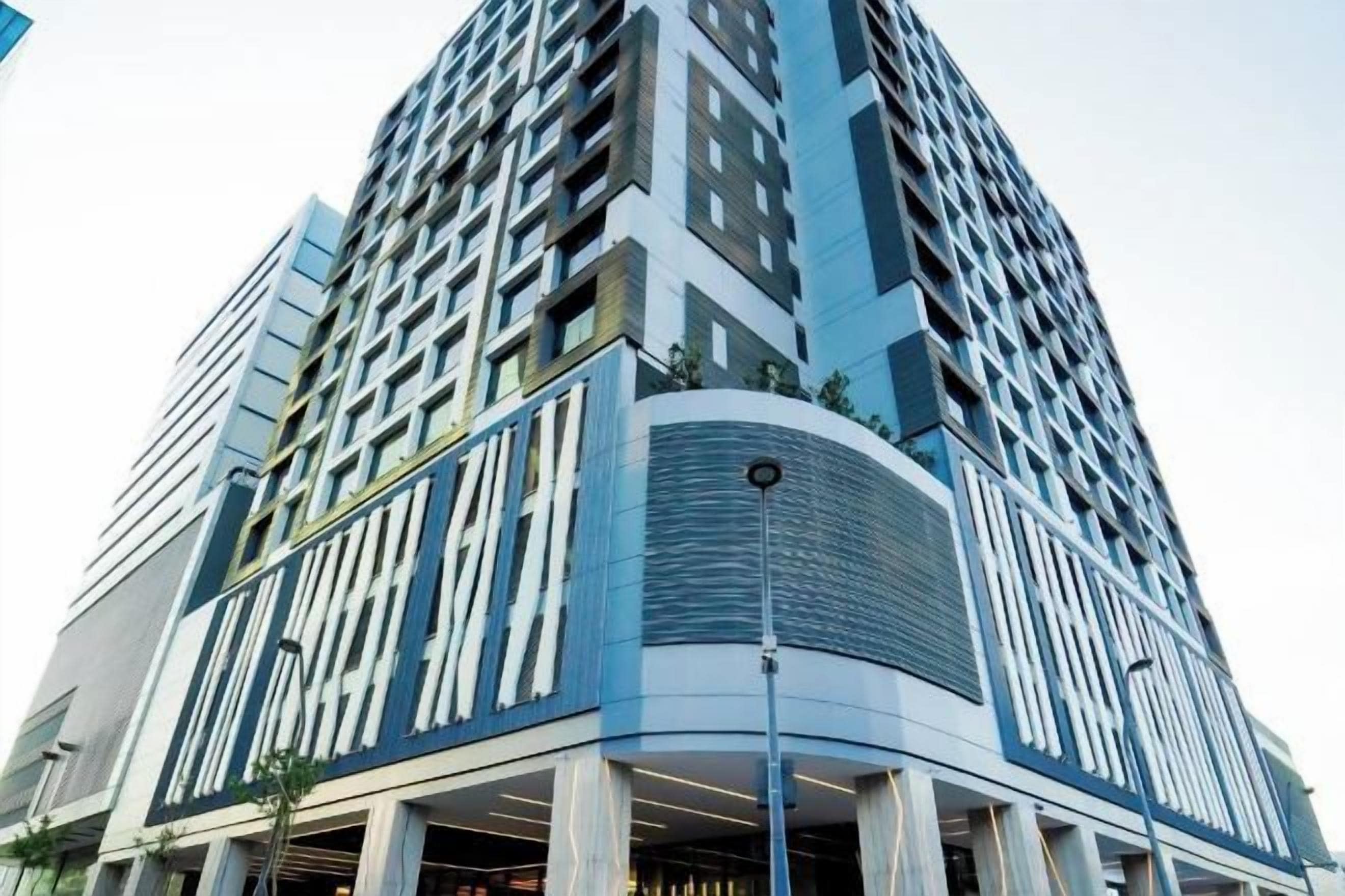 A modern high-rise building with a curved facade, large windows, and a prominent entrance.
