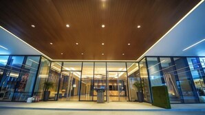 Une entrée moderne, avec des portes en verre et un plafond en bois.