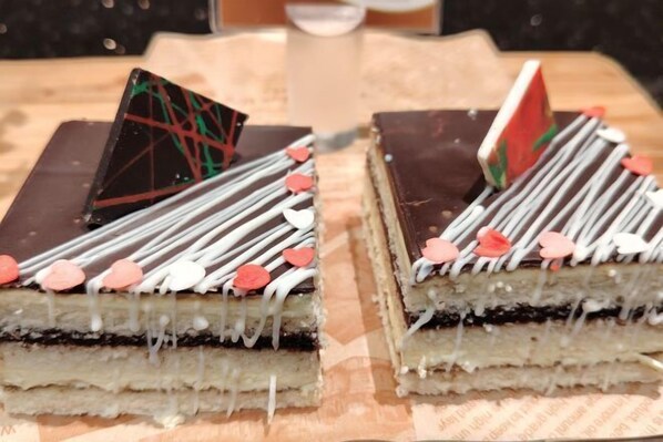 A layered dessert with white and red decorations on a wooden surface. - Bayprime Hotel (Paranaque)