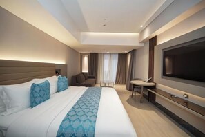 A modern hotel room with a large bed, a flat-screen TV, a desk, and a chair. - Bayprime Hotel (Paranaque)