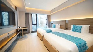 Une chambre d’hôtel avec deux lits, un bureau et une grande fenêtre.