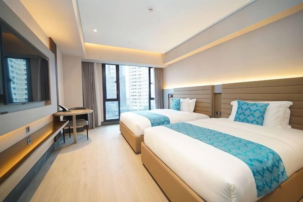 Ein Hotelzimmer mit zwei Betten, einem Schreibtisch und einem großen Fenster.