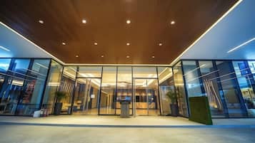 A modern building entrance with glass doors and a wooden ceiling.