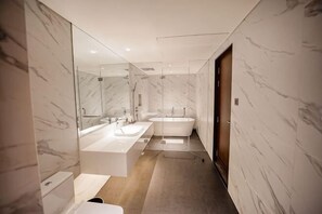 A modern bathroom with a large mirror, a bathtub, and a separate shower area. - Bayprime Hotel (Paranaque)