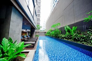 A modern indoor pool area with lounge chairs and greenery. - Bayprime Hotel (Paranaque)