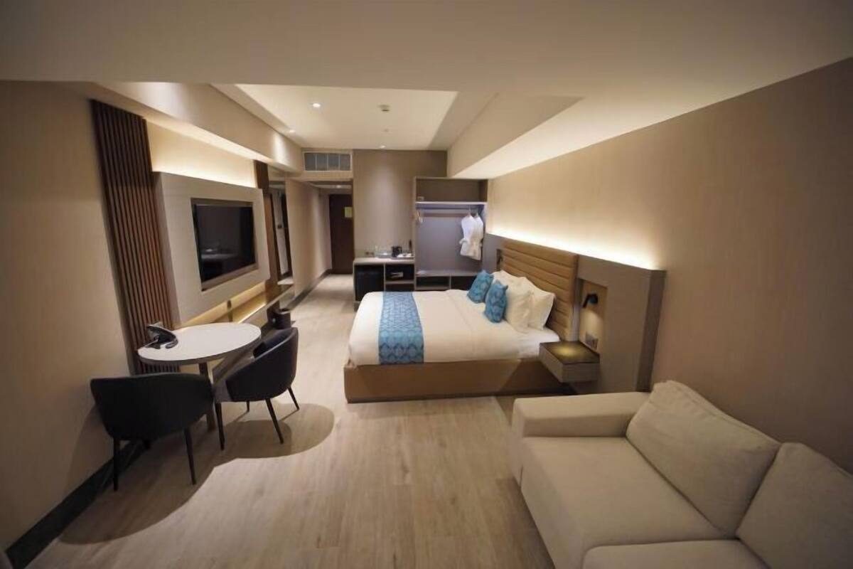 Ein Hotelzimmer mit einem Bett, einem Schreibtisch, einem Fernseher, einem Sofa und einem Sessel.