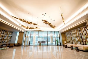 En rymlig lobby med modern design, med en sittgrupp, en receptionsdisk och en stor glasvägg som ger utsikt över omgivningen.