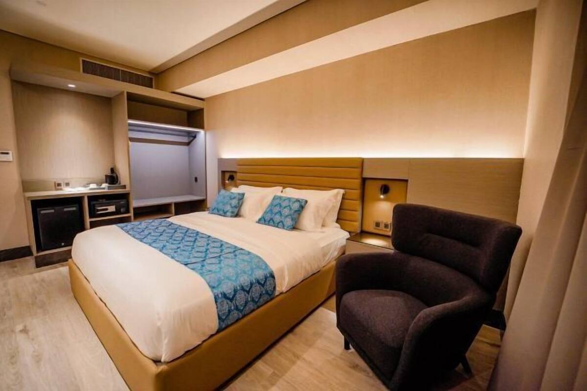 Ein Hotelzimmer mit Bett, Sessel, Schreibtisch und Fernseher.
