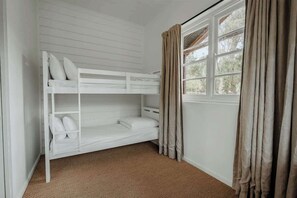 A bunk bed room with a window and curtains.